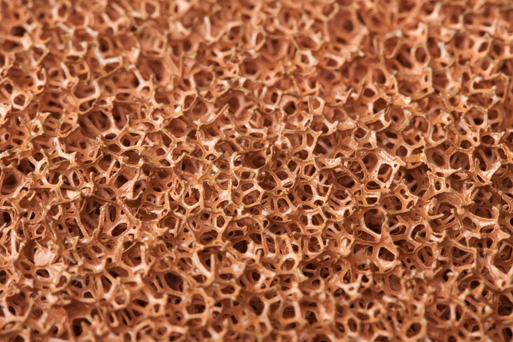 A close up of solid orange-coloured metal foam. 