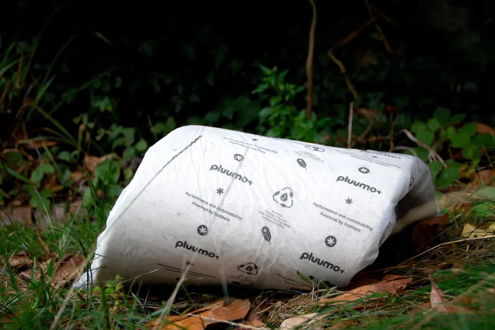 White rolled-up packaging that says pluumo+ on a patch of grass