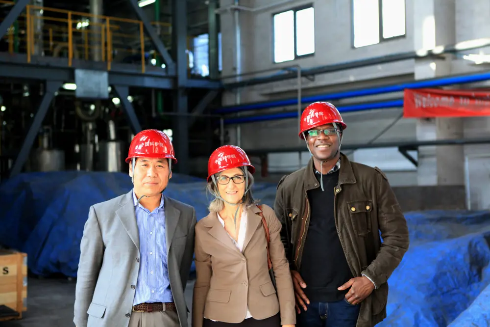 A photograph of three people in red hard hats inside a factory.