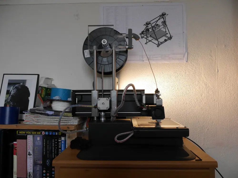 A home-built 3D printer on a bookshelf.