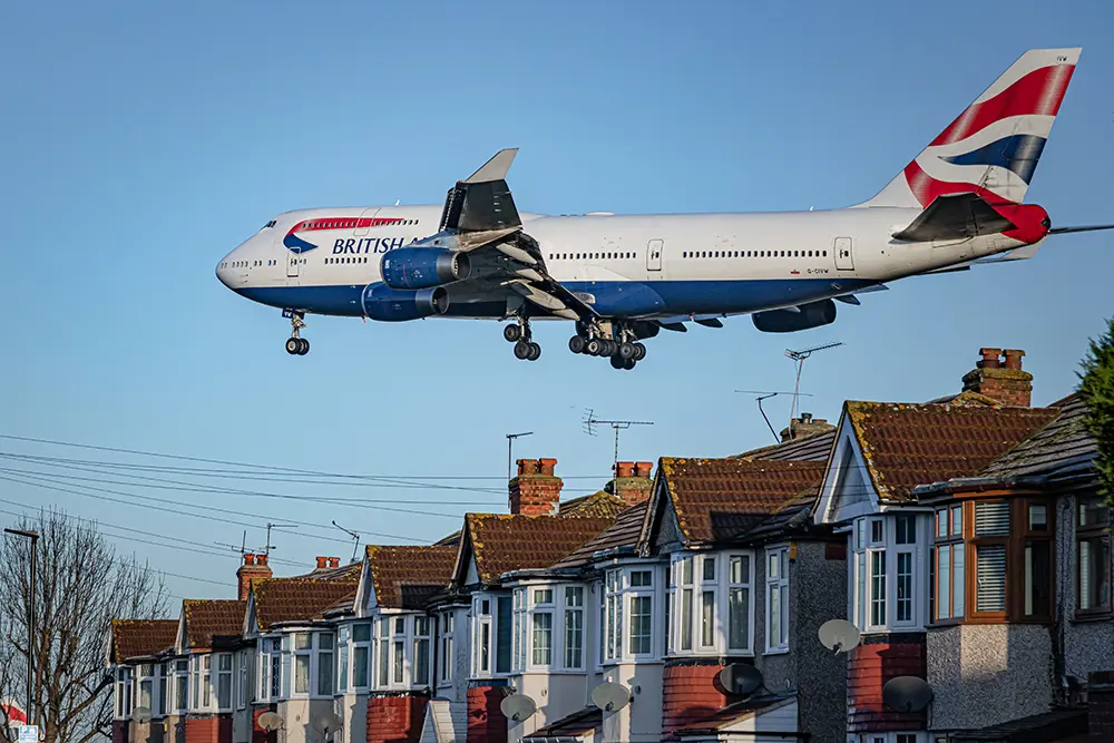 An aeroplane flies over a row of terraced houses