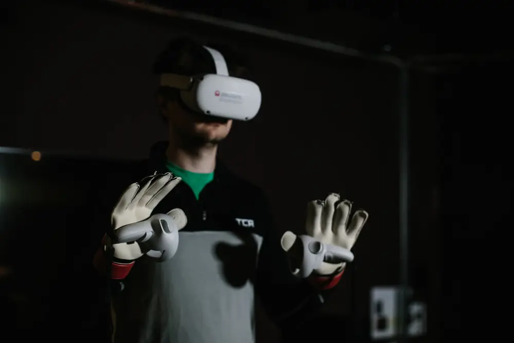 A man wearing a virtual reality headset and handheld controllers on top of his goalie gloves.