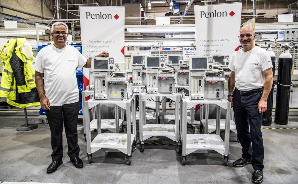 Two engineers standing either side of a VCUK ventilator prototype.