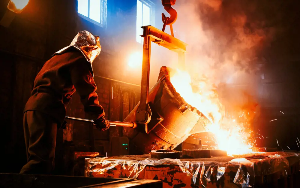 A worker at a metallurgical plant pouring molten metal into a mould.