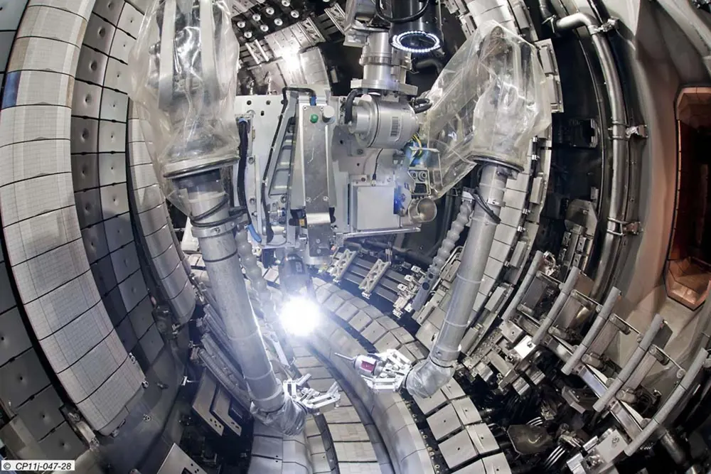 A photo of the inside of the JET tokamak showing two robot arms carrying out repairs.