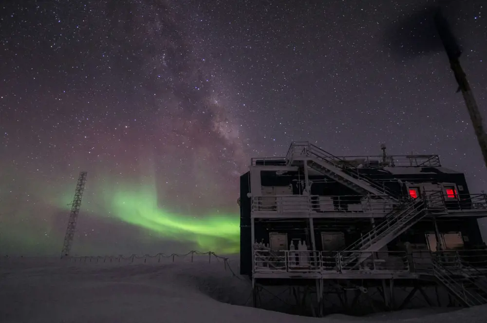 white multi-storey building in the snow under starry night and northern lights