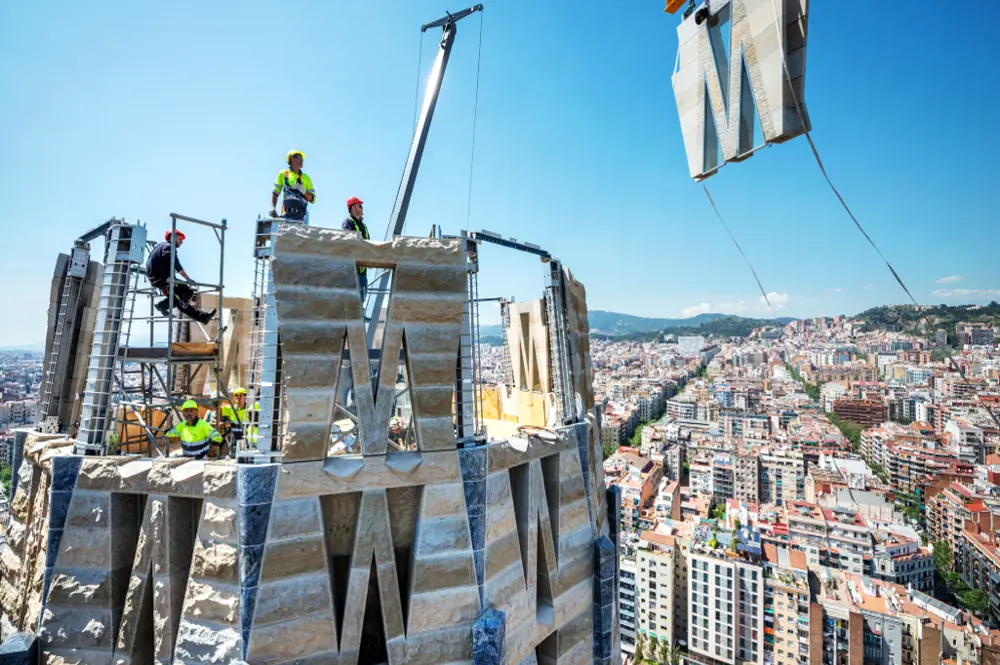 Construction workers on the top of the virgin Mary Tower, placing the prestressed Masonry panel on the tower with a crane.