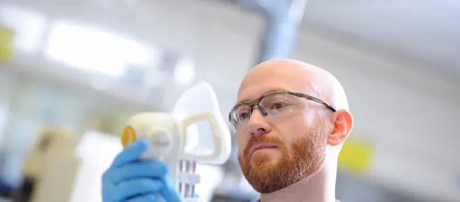 A person holding an Owlstone Medical device that captures breath samples.