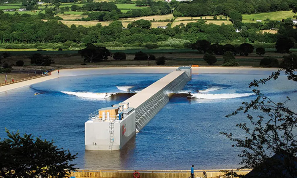 A large body of water outside with a wave generator and surfers.
