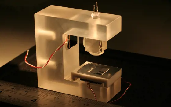 The gravimeter placed next to a ruler for scale. The device includes an LED light source, micro-electromechanical systems and a photodiode (i.e. a shadow sensor).