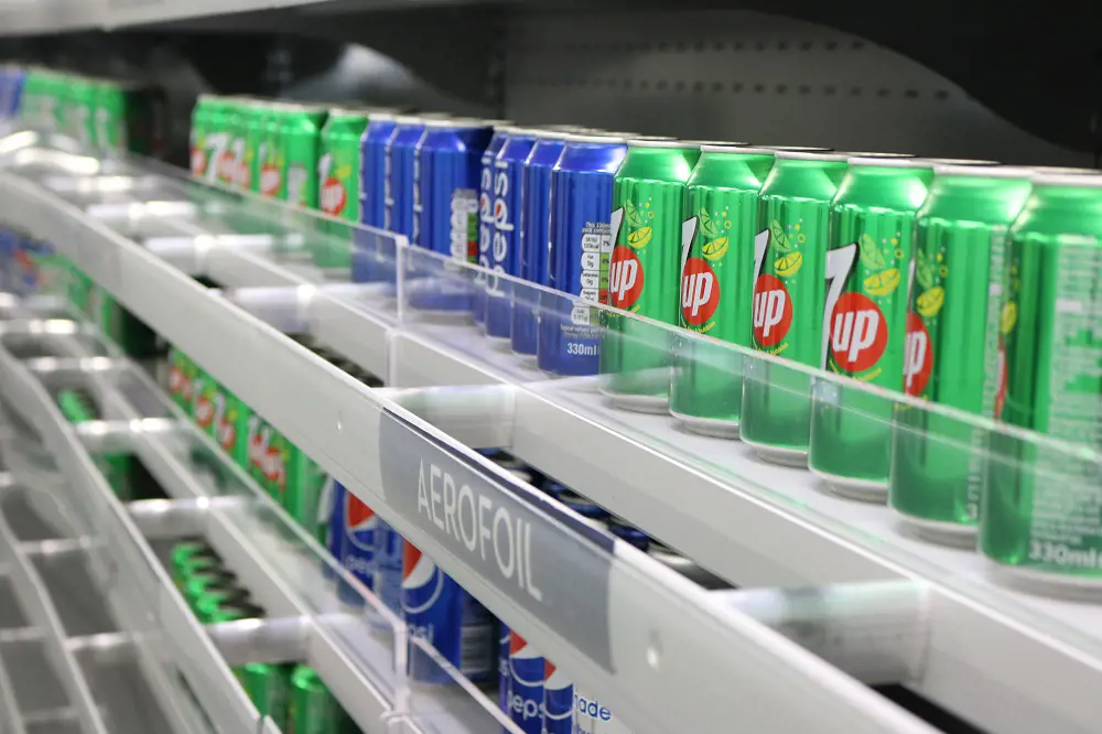 An aerofoil technology shelf with fizzy drinks cans stacked on the shelf.