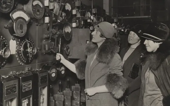 A monochrome photograph of three women on a tour of an early power station.