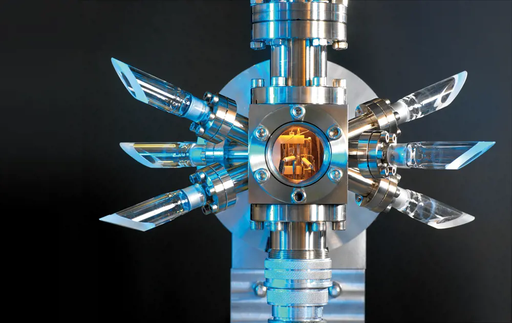 An metal atomic clock, with a central vacuum chamber, against a black background