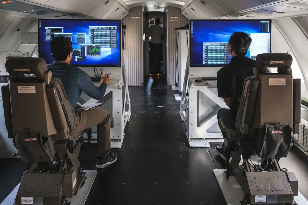 Two launch engineers looking at screens containing data on the flight deck of the Cosmic Girl plane. 