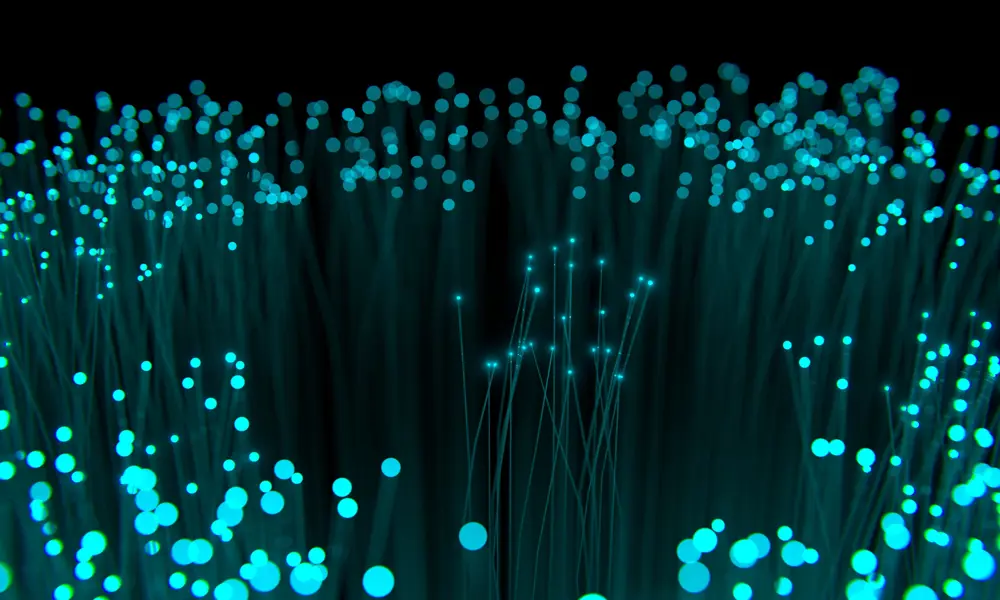 A artistic representation of a collection of optical fibres with light being transported to the end of the fibre. 