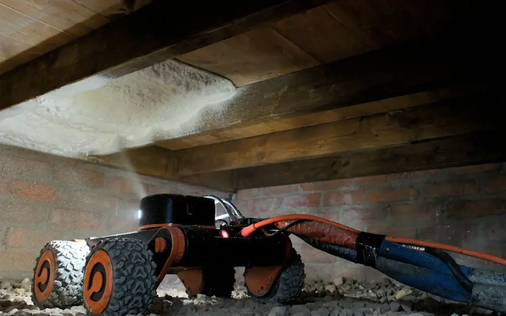 A Q-Bot with four wheels, inside an underfloor cavity. It is lighting up the area in front of it to help with navigation.