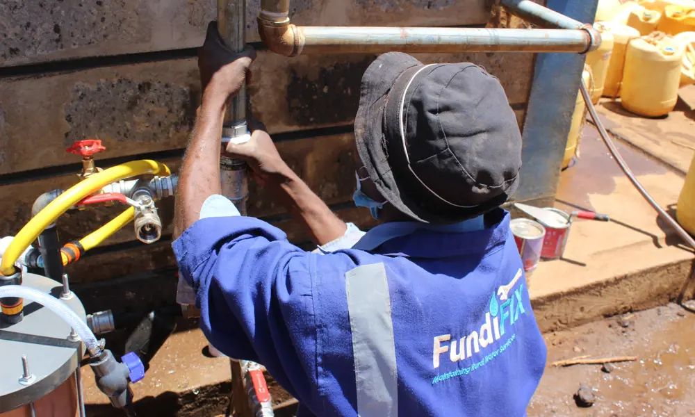 A technician wearing a Fundifix boilersuit, maintaining an outdoor water system.