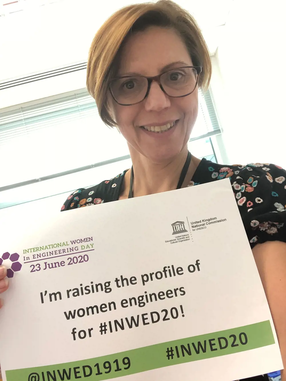 Dr Luisa Freitas dos Santos holding a paper that says 'I'm raising the profile of women engineers for #INWED20!'