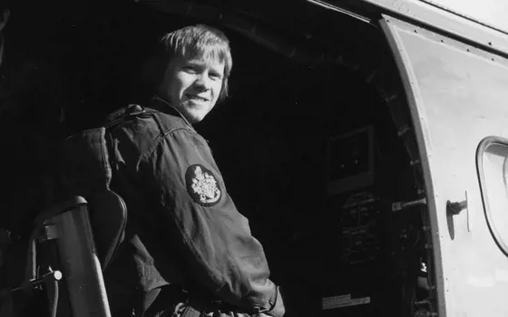 A black and white photograph of a young man sitting in a helicopter.