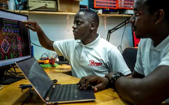 Two electrical engineers designing hardware for a security system using computer aided design software on their computers.