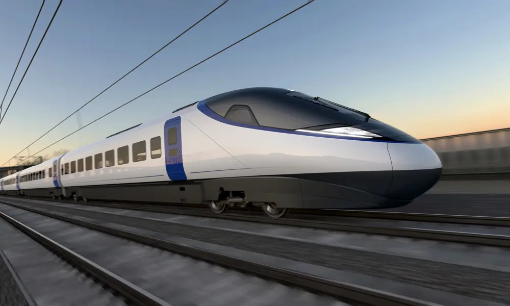 Artist’s impression of a sleek, modern high-speed train traveling on railway tracks. The train has a streamlined design with a pointed nose, white body, and blue accents around the doors. Overhead electric wires run above the tracks, and the background shows a blurred landscape under a clear sky at sunset, suggesting speed and motion.