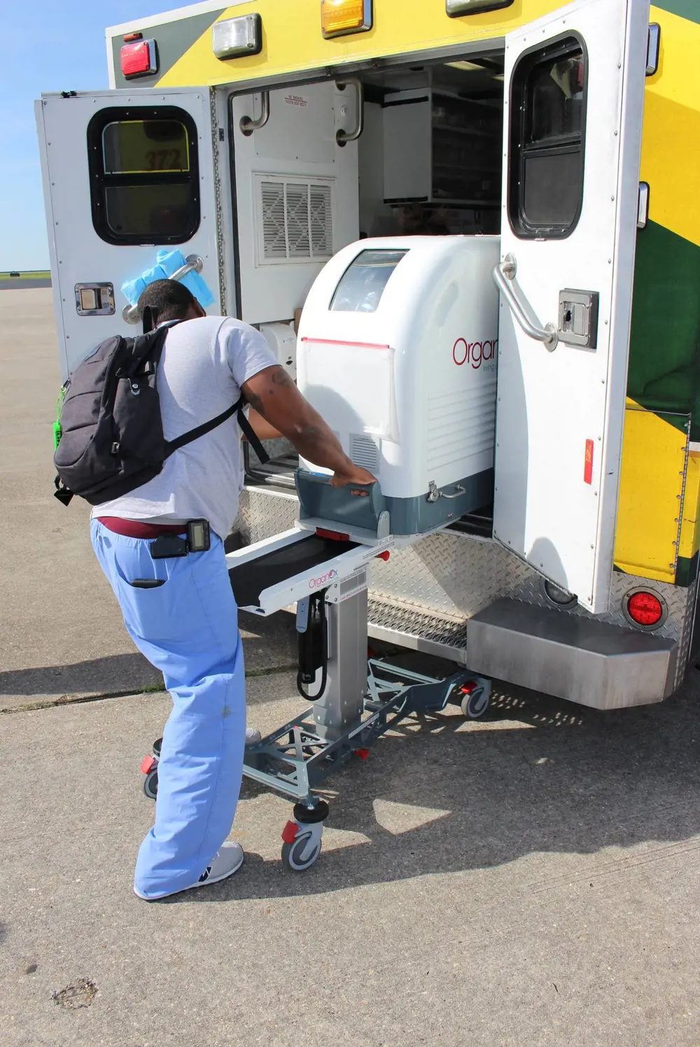 The OrganOx metra container being loaded into the back of an ambulance using a stand on wheels to slide it in.