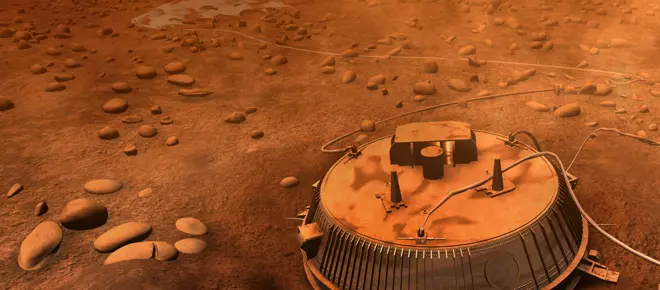 Artist’s impression of the Huygens probe resting on Titan’s rocky surface, with an orange haze and scattered stones under a thick atmosphere.