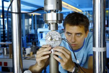 Dr Henk Jonkers places a sample block of self-healing concrete into a machine that will create cracks on the surface