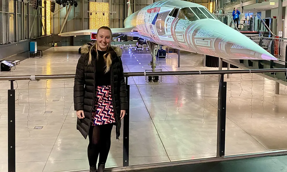 Person standing in a museum gallery beside a Concorde aircraft, with the plane’s nose and exhibition space visible behind.