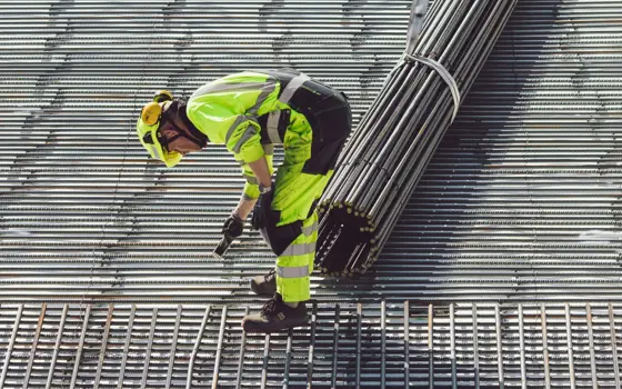 An engineer working with steel for a foundation, wearing a hard hat.