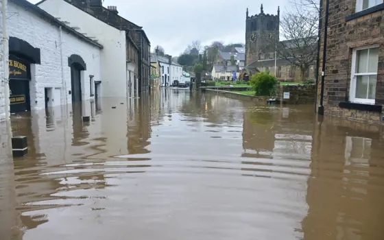 A street in a UK village that has been flooded, with floodwaters rising over a metre from the ground.