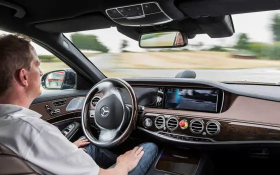 A man sitting in a moving car autonomous vehicle, with his hands on his lap.