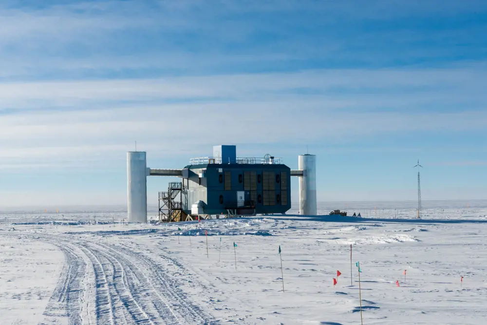 A boxy structure amid a snowy landscape on a sunny day.