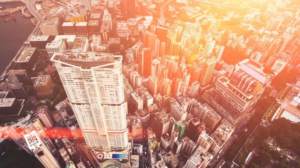 High-angle view of a dense city skyline with tall buildings and sunlight illuminating the urban landscape, representing modern infrastructure challenges.