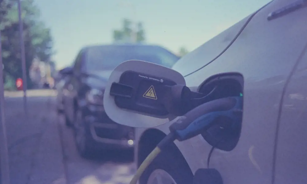 A close up of an electric car being charged on the side of the road.