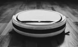 A black and white close up picture of a robotic vacuum.