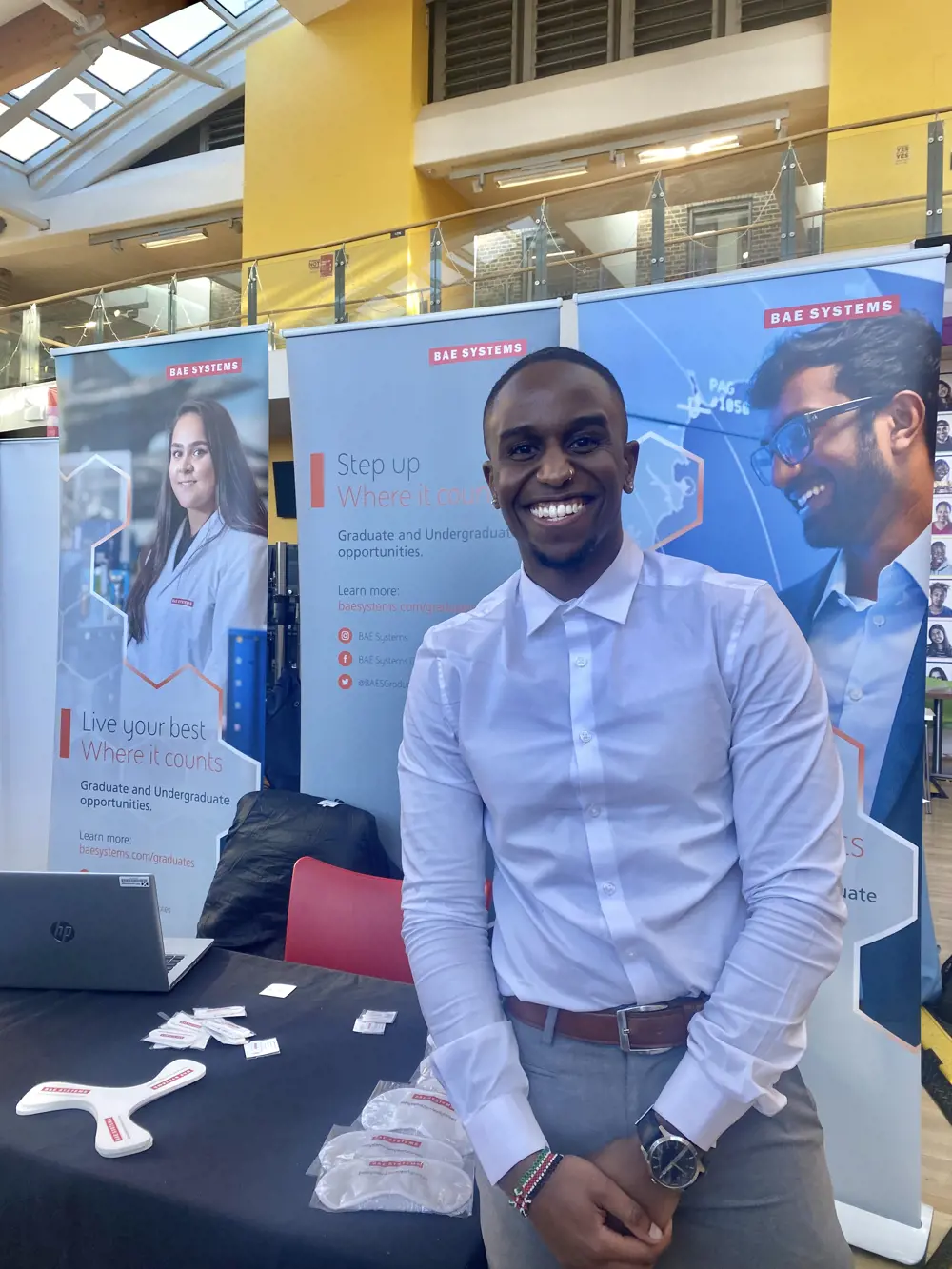 An aerospace engineer standing in front of a BAE Systems desk at a careers fair.