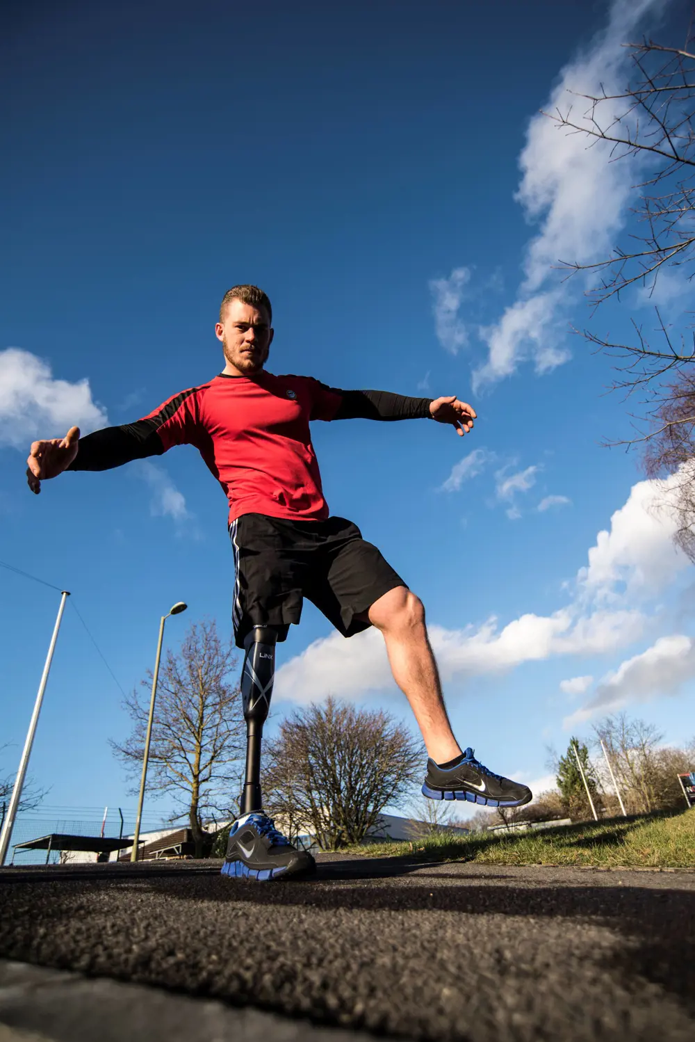 A man in sporting gear balancing on a Linx limb prosthetic leg.