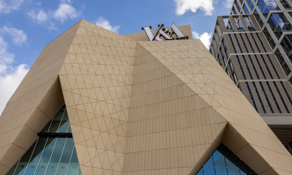 Upward view of V&A East’s sculpted façade and prominent V&A sign.