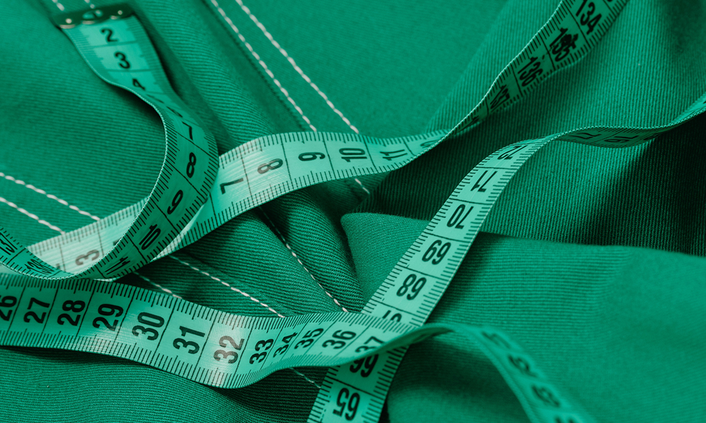 A green tape measure lying on top of green-coloured denim