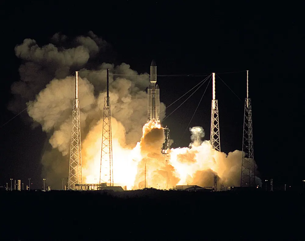 Rocket carrying the Cassini–Huygens mission lifts off at night, surrounded by bright exhaust flames and large clouds of smoke at the launch pad.
