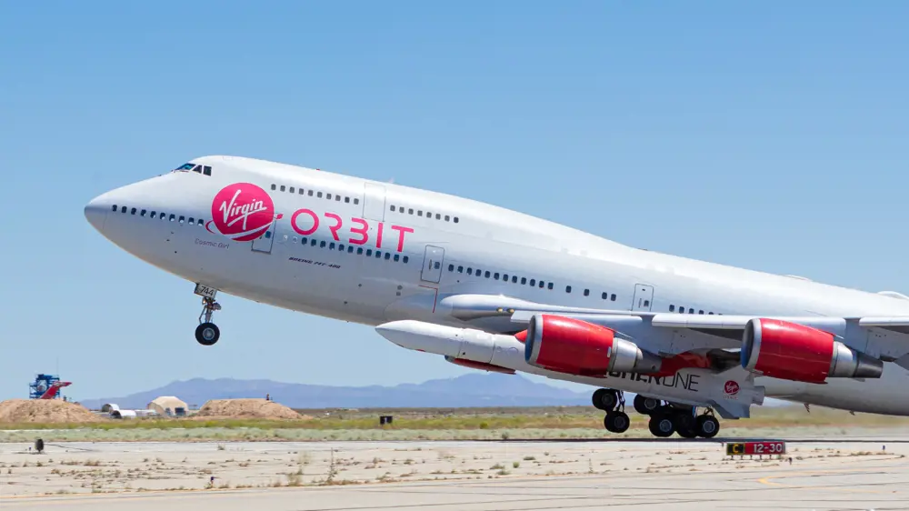 A Boeing aircraft that says "Virgin Orbit" on the side, with LauncherOne rockets attached to the bottom. Used for horizontal launch.
