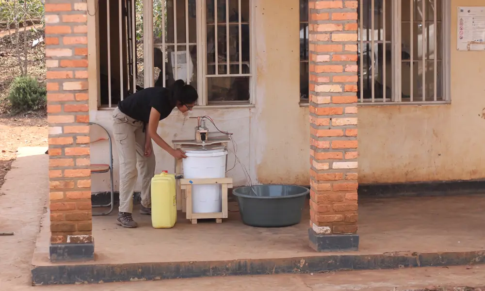 Aakeen Parikh looking at an off-grid washing machine outside a building in Minazi, Rwanda,. 