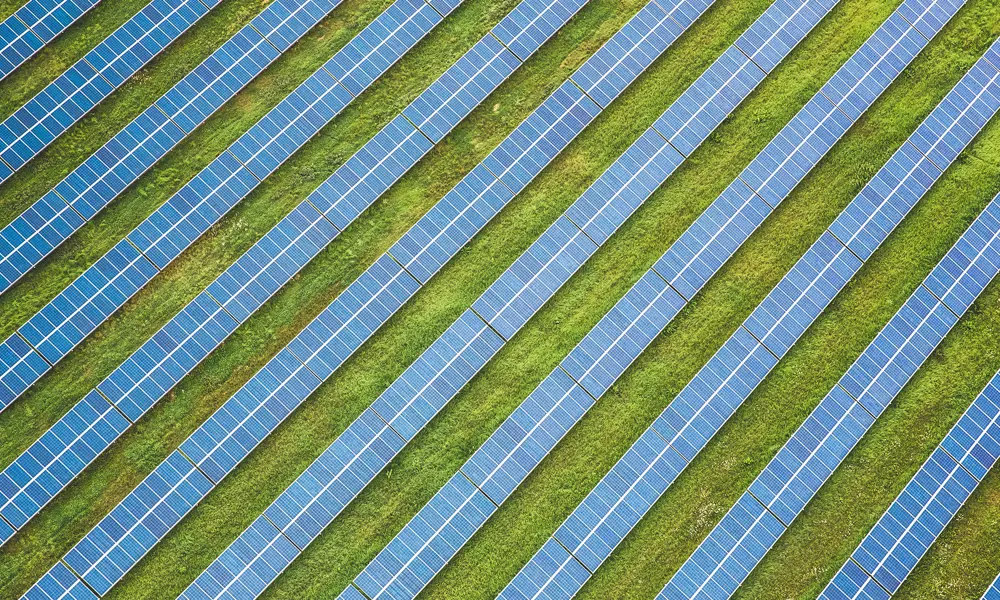 Parallel arrays of solar panels seen from above in a field.