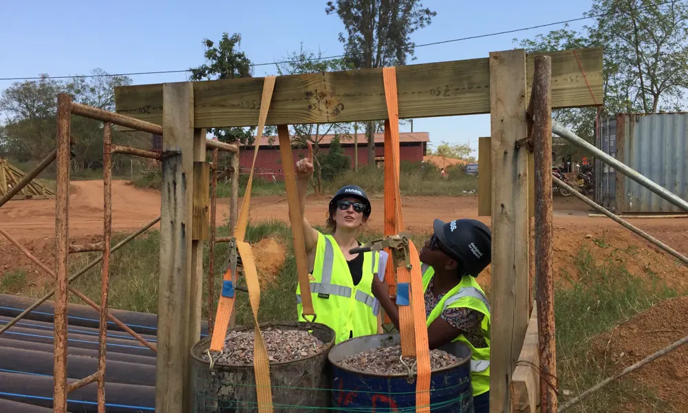 Rosie Goldrick in Rwanda, standing in a construction area with a colleague. 