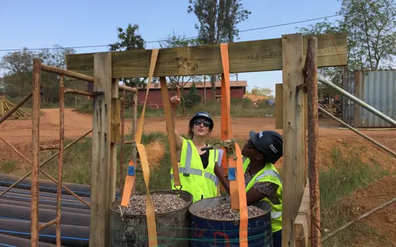 Rosie Goldrick in Rwanda, standing in a construction area with a colleague. 